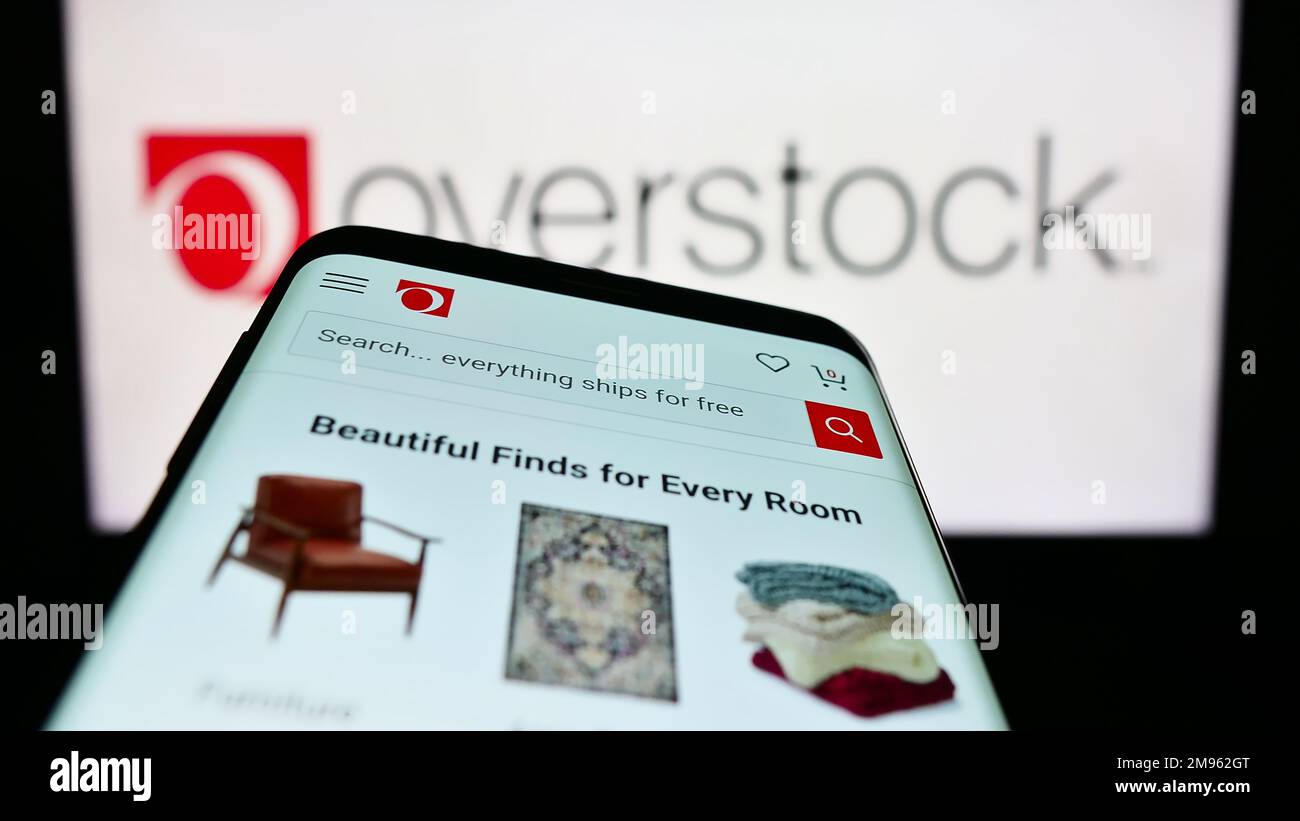 Mobile phone with webpage of US e-commerce company Overstock.com Inc. on screen in front of business logo. Focus on top-left of phone display. Stock Photo