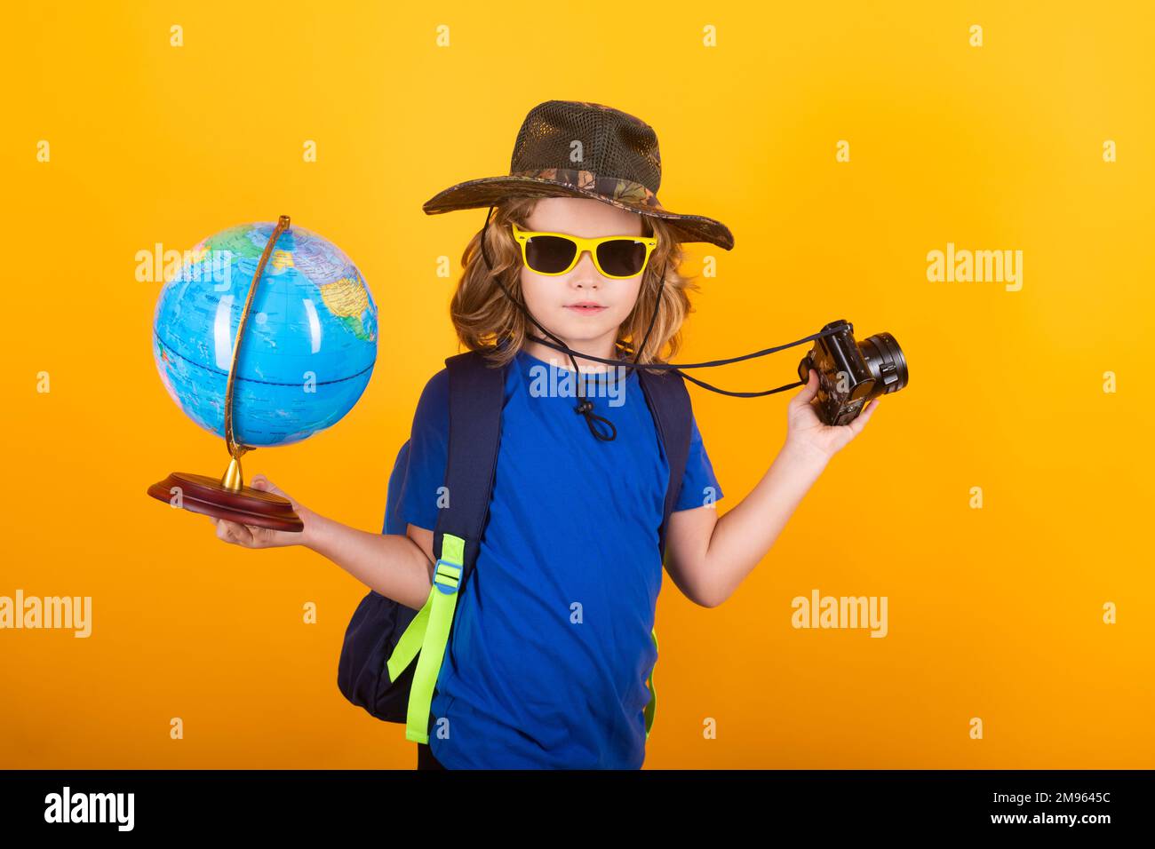 Travel and adventure concept. Little child boy tourist explorer with globe world. Discovery, exploring and education. Studio isolated portrait. Stock Photo