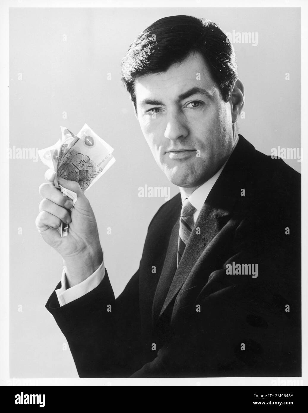 A dashing man clutches a fistful of pound notes Stock Photo Alamy