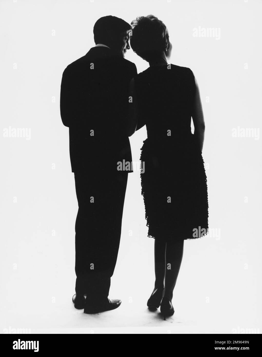 A silhouetted couple face away from the camera in evening apparel. Stock Photo