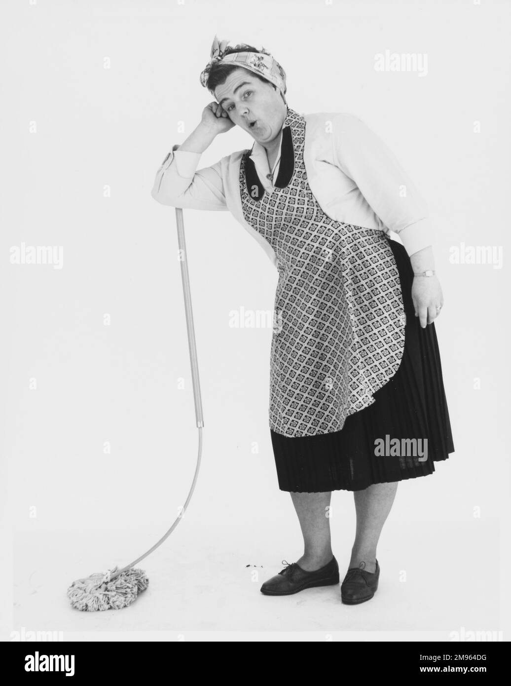 A stereotypical cleaner leaning on her mop. Stock Photo