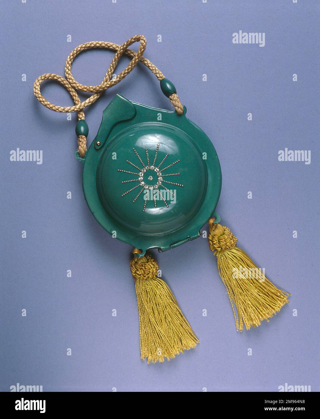 Green circular compact with diamante (paste) decoration, gold cord and tassels containing a mirror, powder and two lipstick holders. Stock Photo