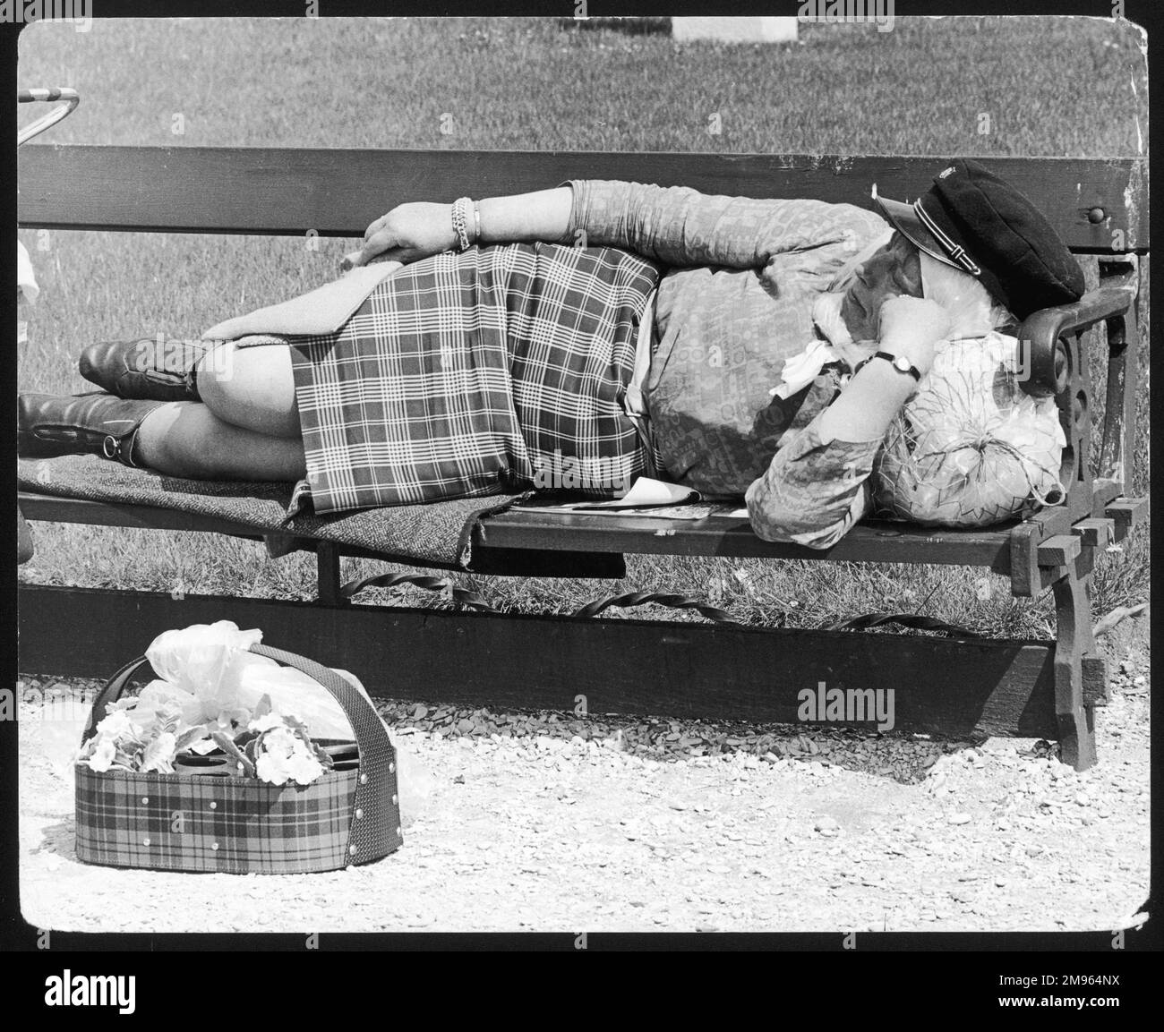 A French bag lady sleeping on a park bench in Paris, France. Stock Photo