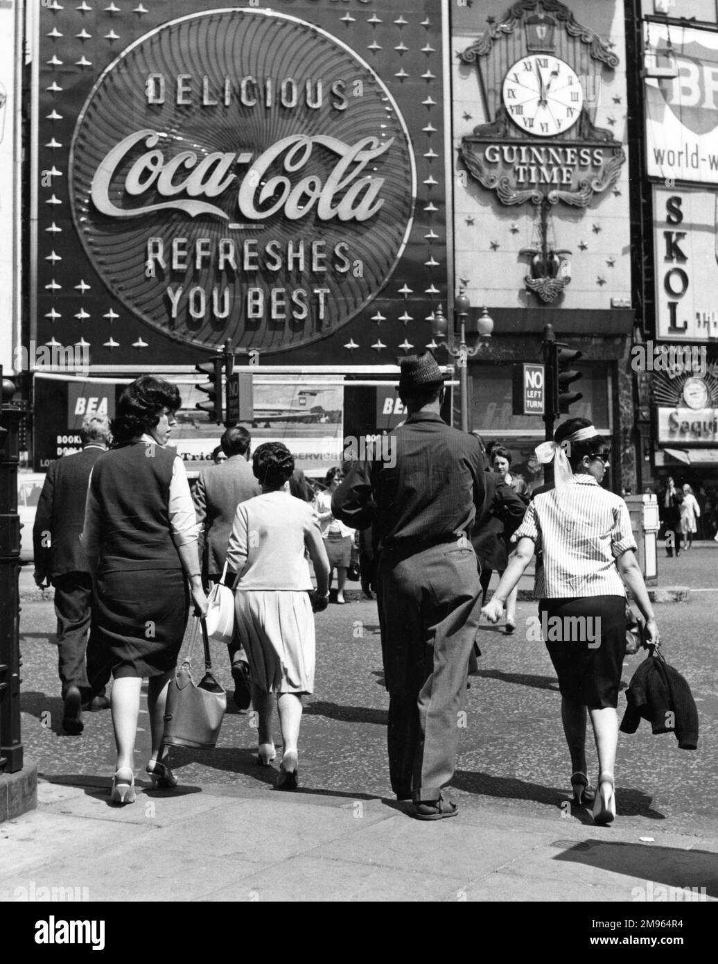 Pedestrians cross the road in front of a huge Coca-Cola advert in Piccadilly Circus. Stock Photo