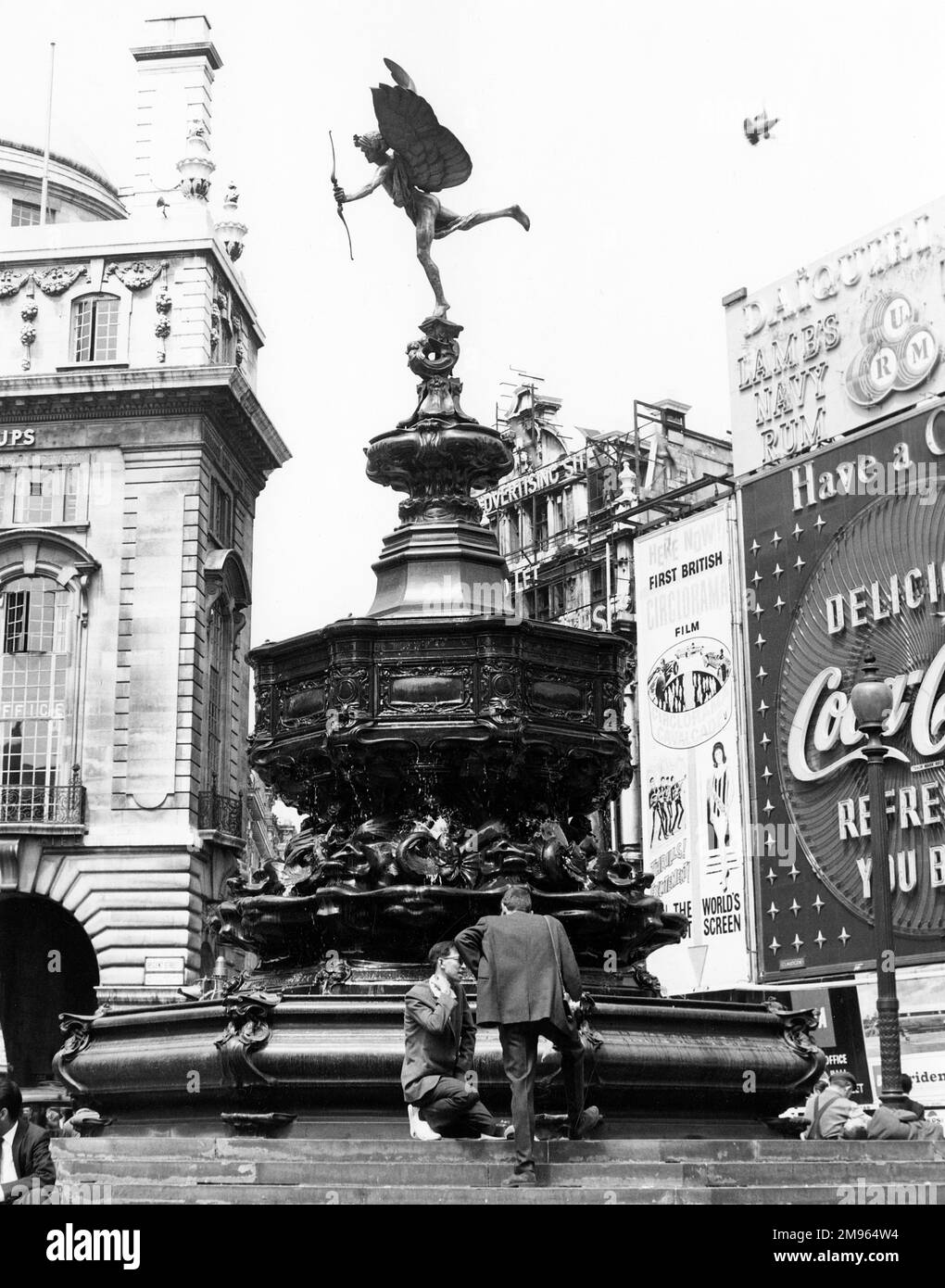 People sit at the base of the statue of Eros in Piccadilly Circus