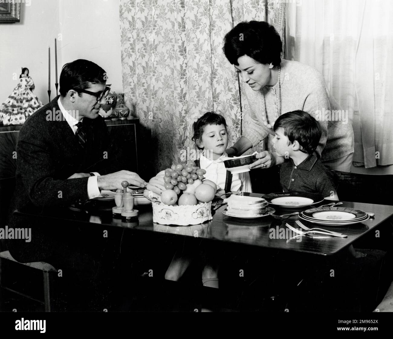 Mum serves up dinner to the rest of the family. Stock Photo