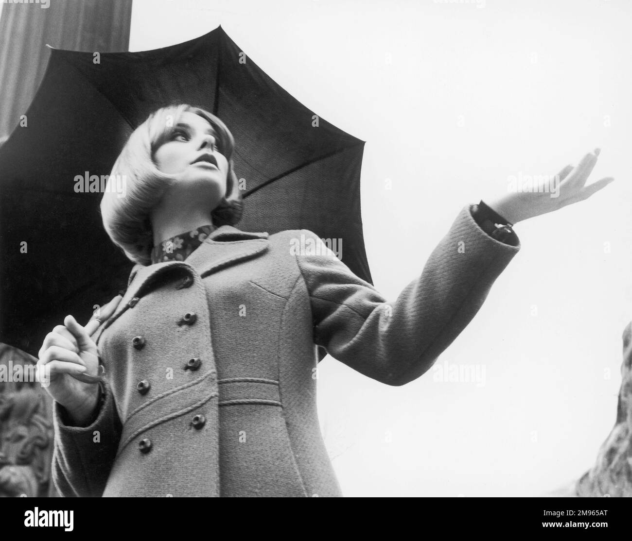 A woman under an umbrella checks to see if it's still raining. Stock Photo