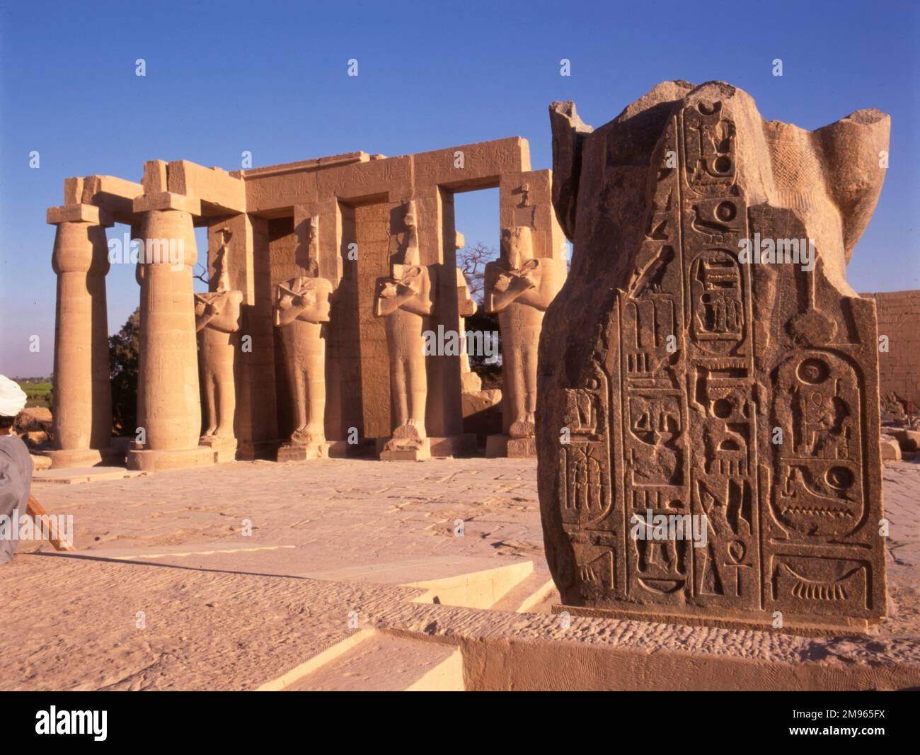 The 'Ramesseum', Thebes (Luxor), Egypt, showing 4 Osiris posts and 2 Papyrus pillars of the 2nd Pylon, with the fallen statue of Rameses II beside them. Stock Photo