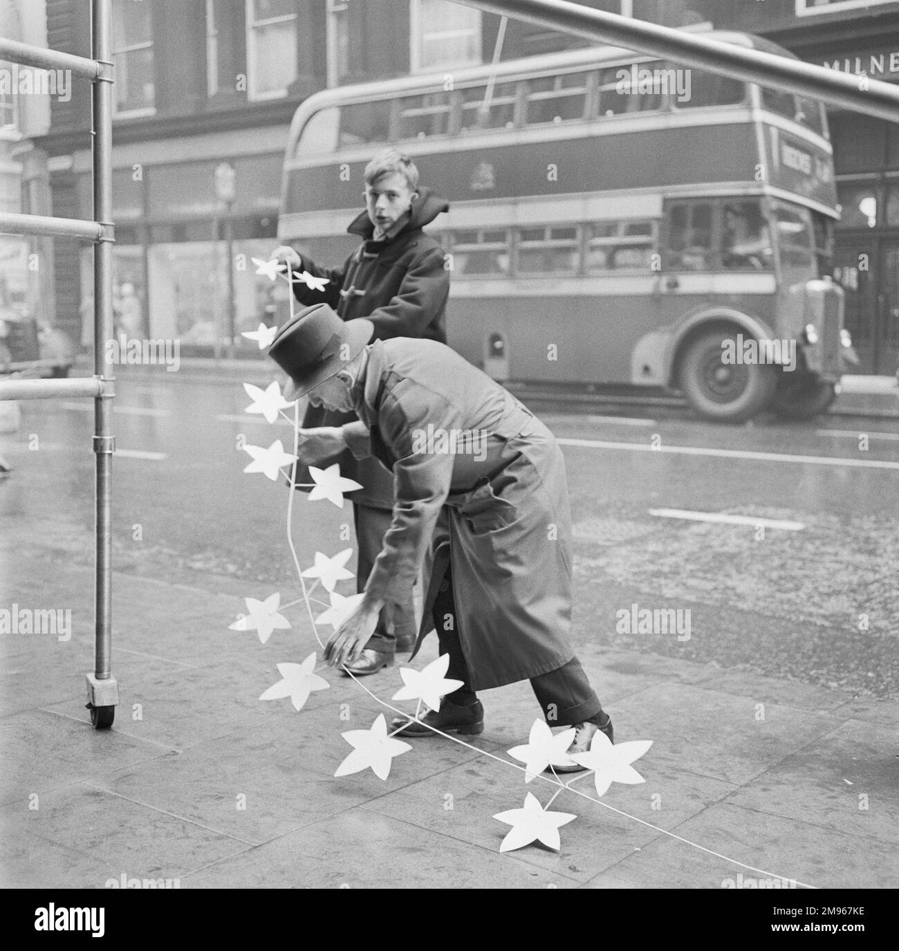 Two men prepare some street Christmas Decorations, Manchester. Photograph by Norman Synge Waller Budd Stock Photo