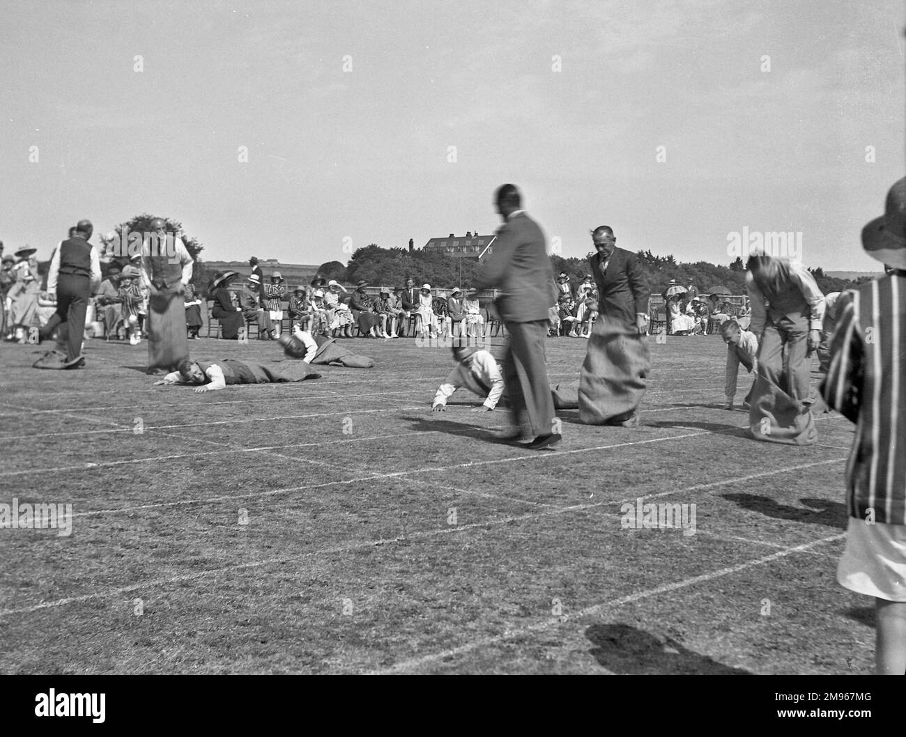 Sporting fathers take part in a sack race designed specially for them at a school sports day in Seaford, Sussex.  Several of them have fallen over, or are in the process of doing so. Stock Photo