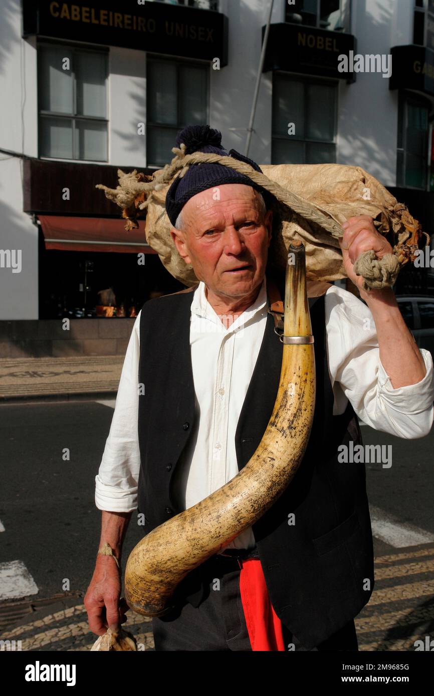 A man belonging to a Porto da Cruz folklore group, carrying a wineskin and a horn, both containing wine.  He is taking part in street entertainment in Funchal, the capital city of Madeira. Stock Photo