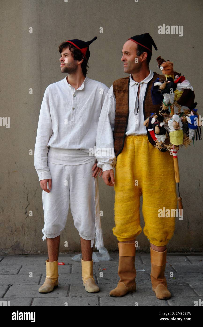 Two young men belonging to a Machico folklore group, wearing traditional costume.  The man on the right is holding a musical instrument known as a brinquinho, a stick decorated with wooden dolls, bells and castanets, which is shaken up and down for the group to dance round.  They are taking part in street entertainment in Funchal, the capital city of Madeira. Stock Photo