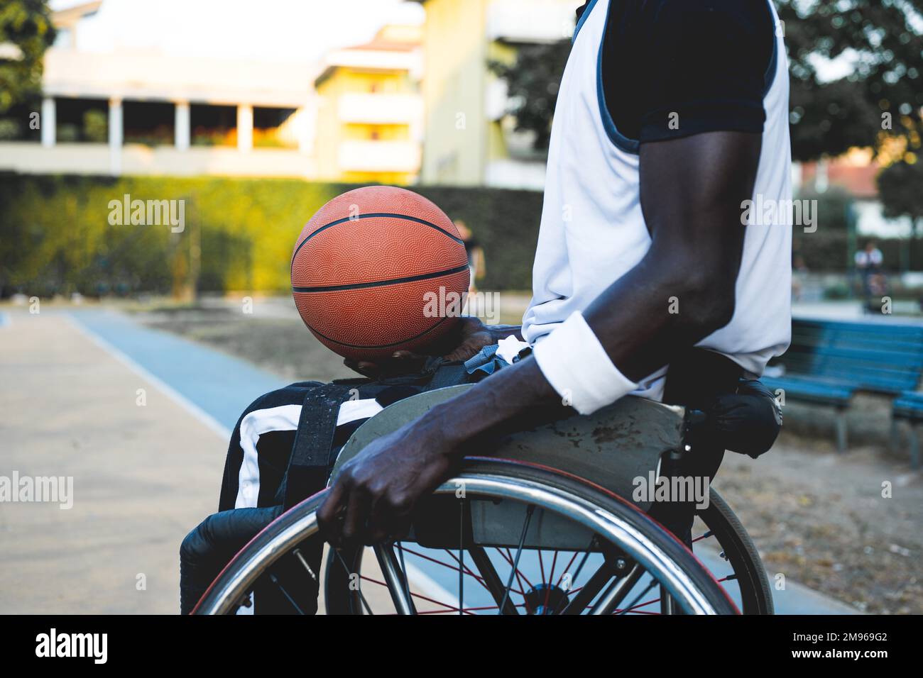 african american basketball player in wheelchair waiting to play on open air ground, concept of accessibility to sports for disabled athlete, social i Stock Photo