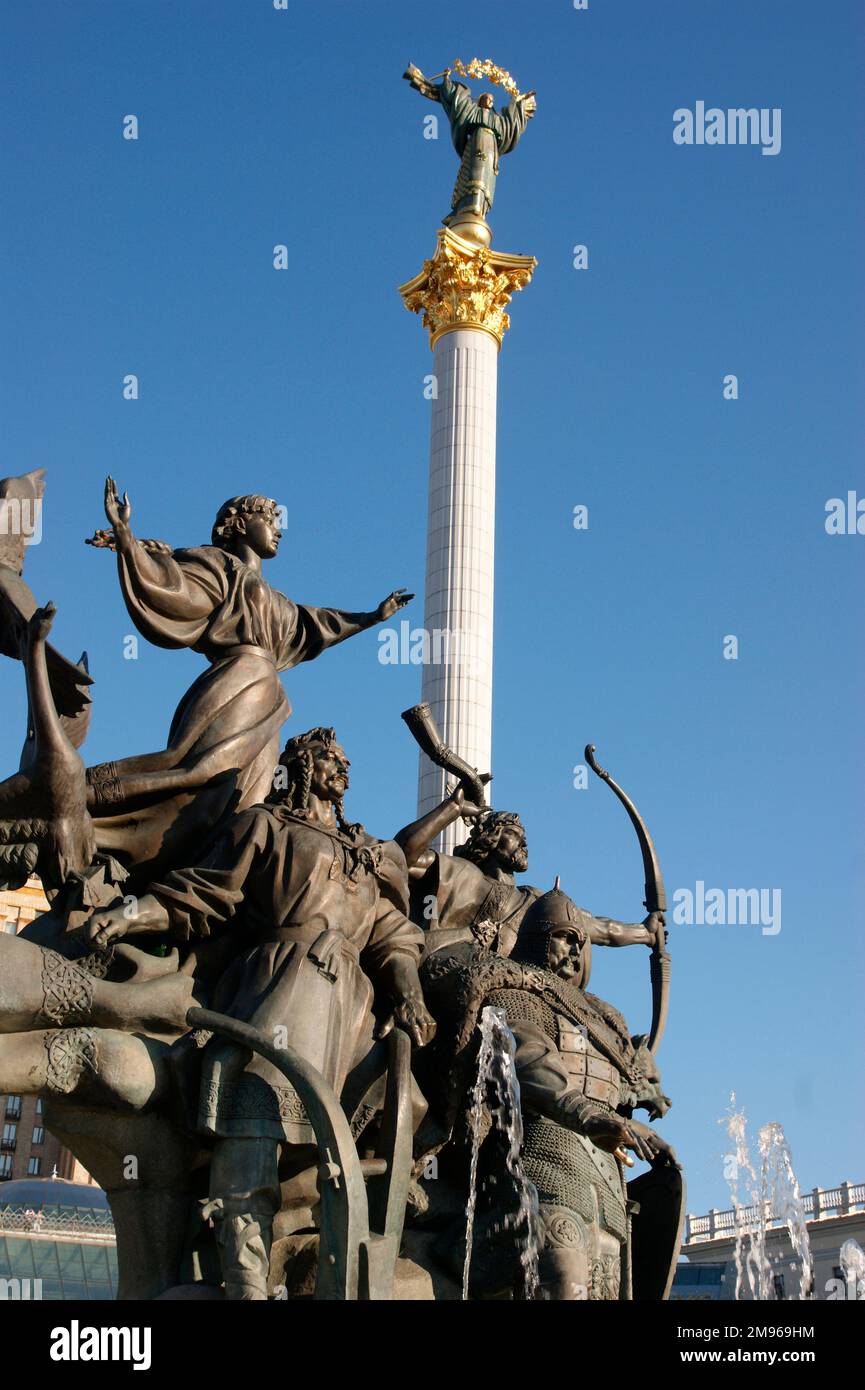 View of a fountain in Independence Square (Maidan Nezalezhnosti) with a monument to the legendary founders of the city of Kiev, the three brothers Kyi (also Kiy, Kij or Kyj), Schek and Khoryv (Khoriv) and their sister Lybid (Lybed). Archaeological excavations have shown that there was an ancient settlement dating back to the 6th century. The names of the founders are linked to geographical features, eg hills, mountains and rivers.  In the middle distance is the white and gold Independence Pillar. Stock Photo