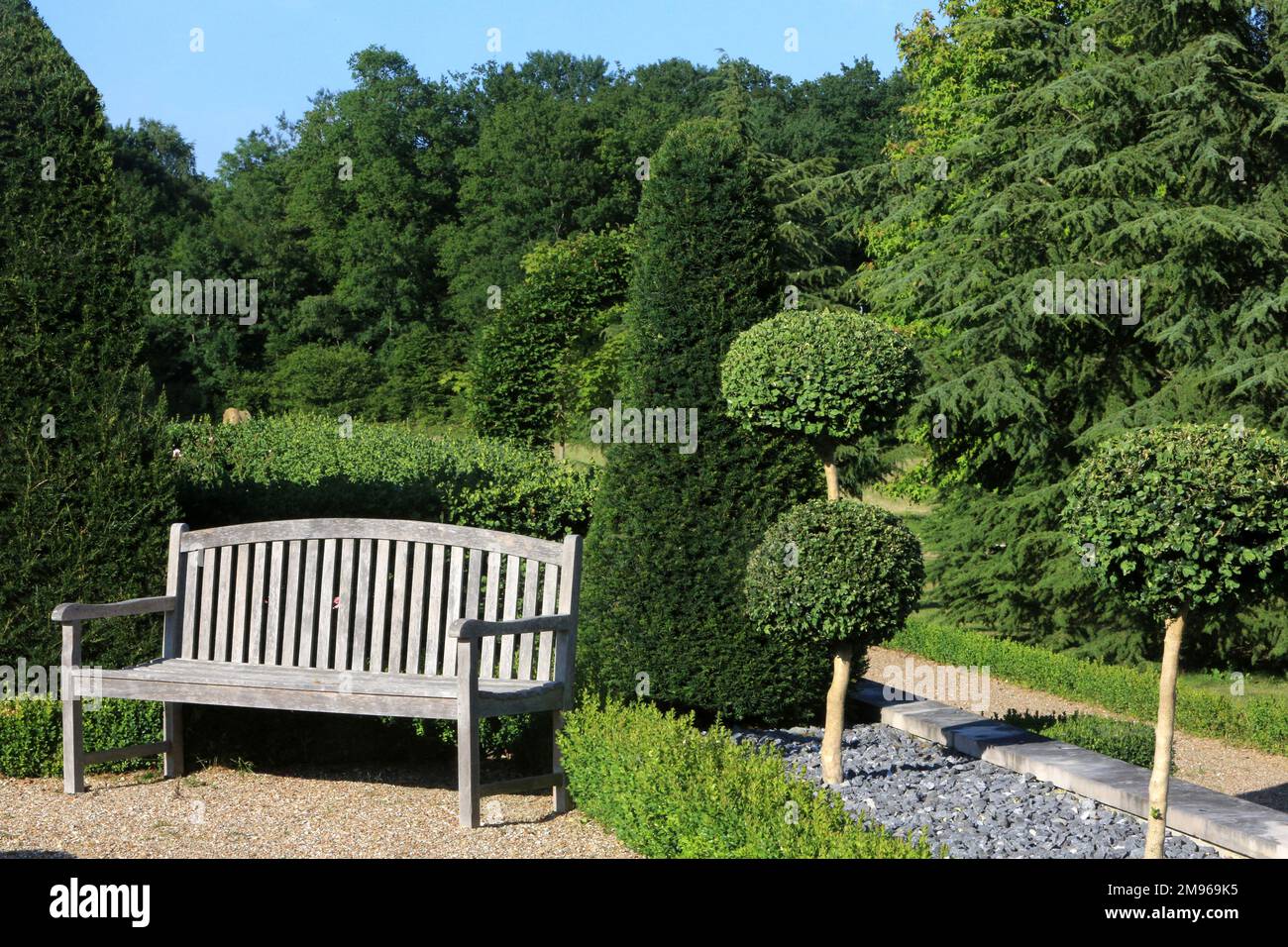 Wooden bench in a landscaped garden. Saint-Sauveur-en-Puisaye. Yonne. Bourgogne. France. Europe. Stock Photo