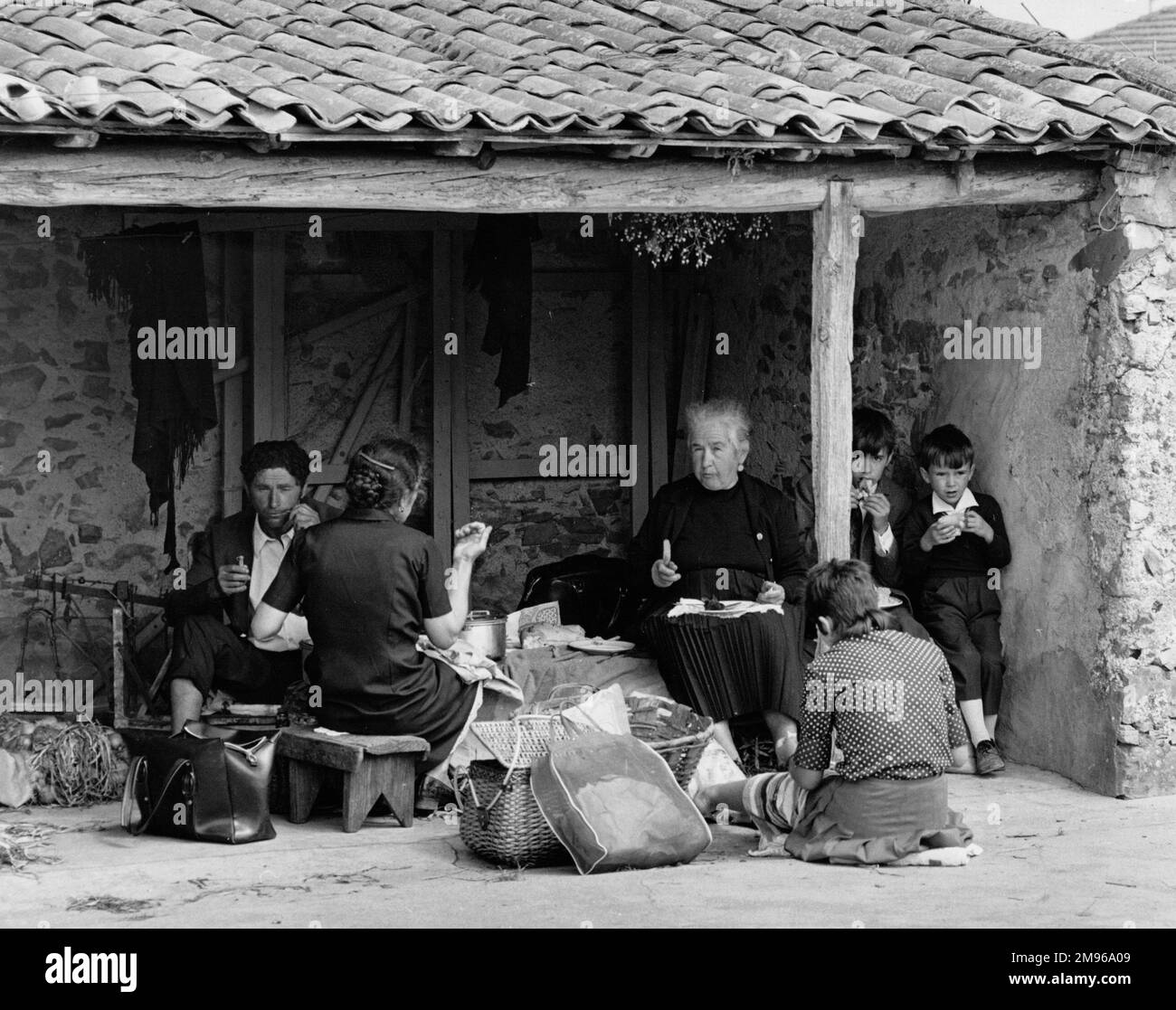 A Portuguese family having a picnic in the shade of a low roof Stock