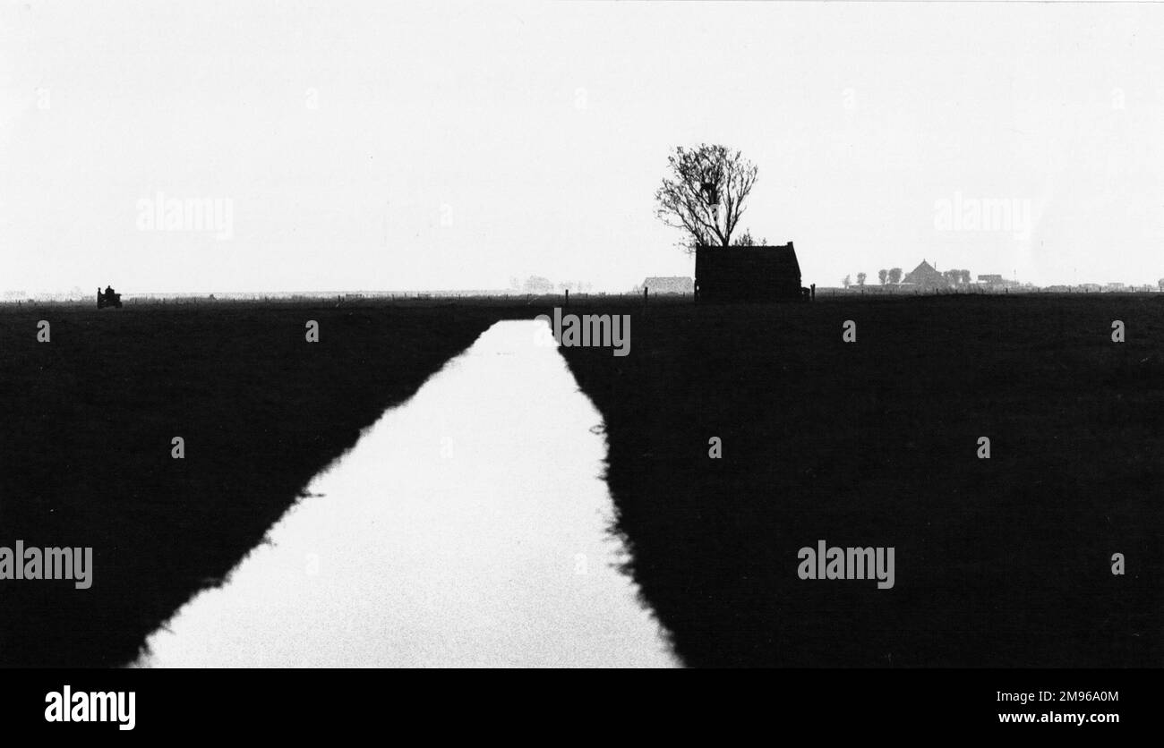 A very flat rural landscape with a water channel stretching towards the