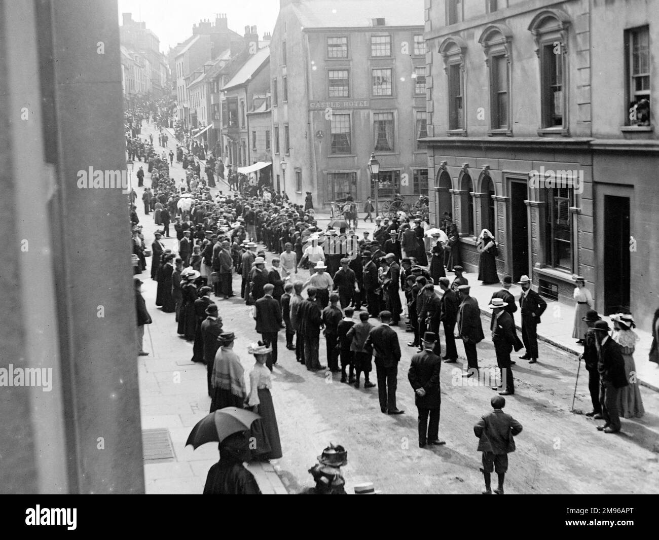 Runners (or are they just fast walkers?) in light coloured clothing make their way along Victoria Place, Haverfordwest, Pembrokeshire, Dyfed, South Wales.  They are watched by crowds of spectators on the pavements and in the roadway. Stock Photo