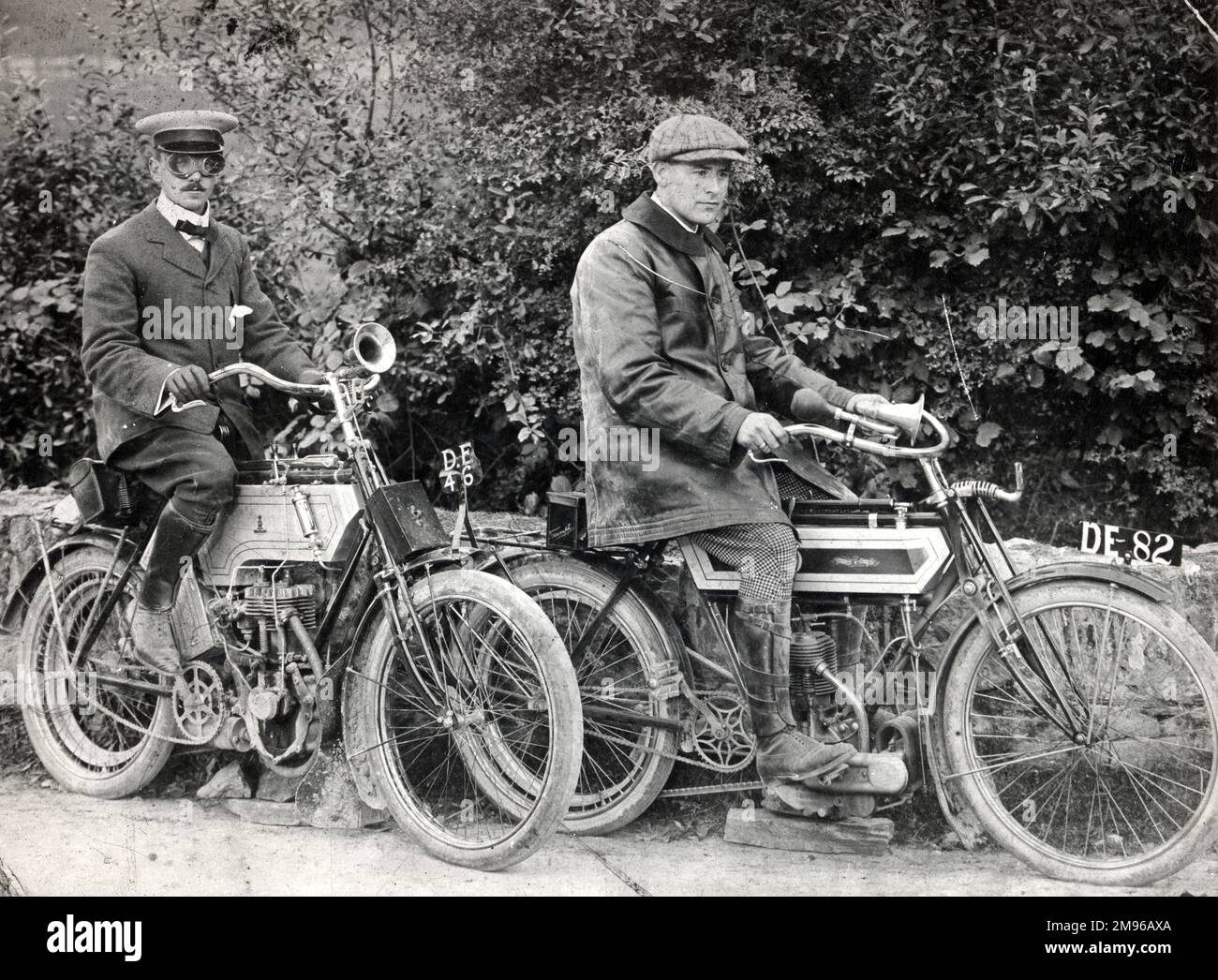 Two Edwardian men on their motor cycles in Pembrokeshire, South Wales.  The man on the right, on a Triumph Imperial, is a member of the Philipps family of Picton Castle.  The man on the left is riding a Raleigh.  The bikes had to be propped up on blocks to avoid wobble during the camera's one-second exposure time. Stock Photo