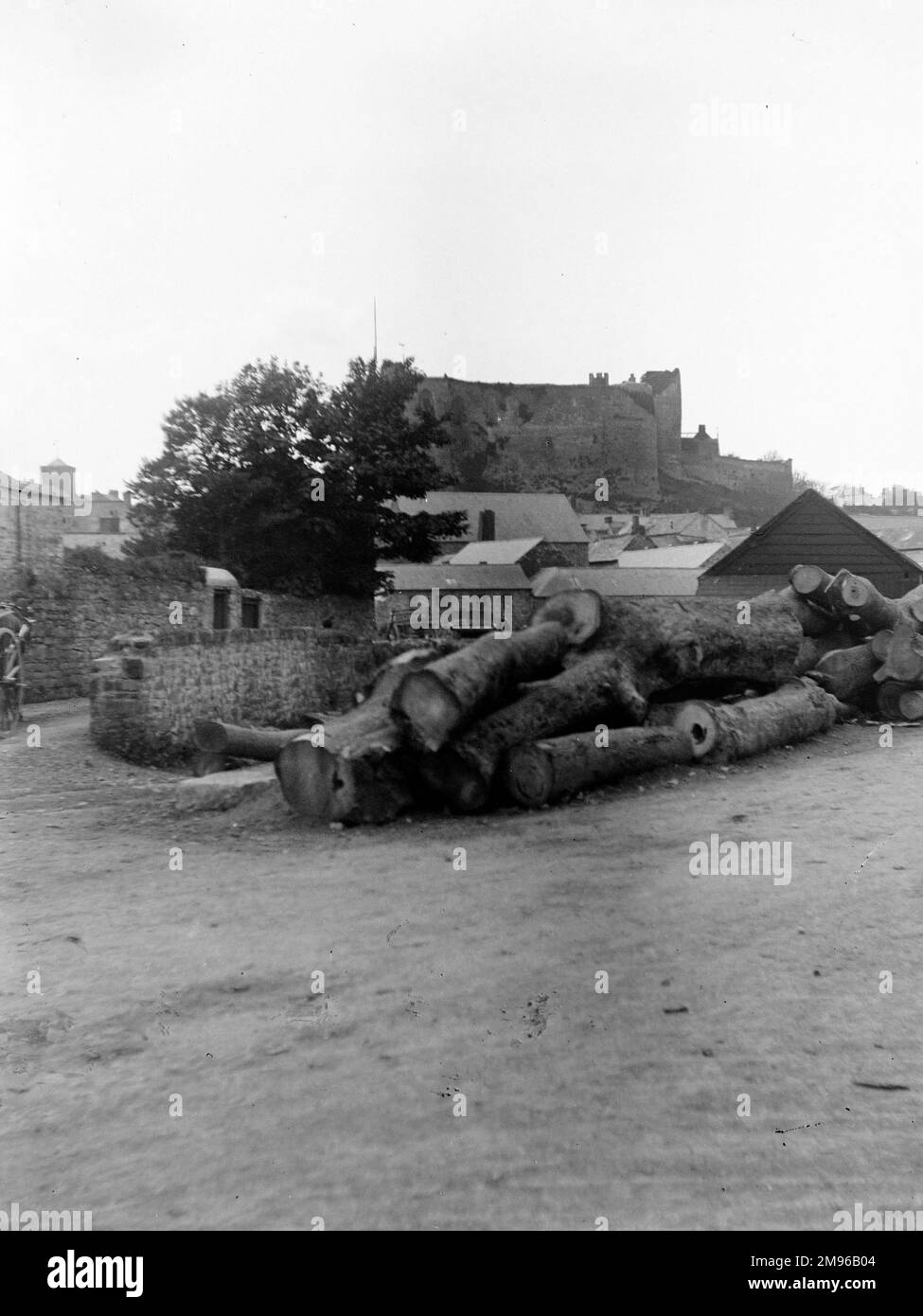 A distant view of the Castle from Old Bridge Street, Haverfordwest, Pembrokeshire, Dyfed, South Wales, with a pile of timber in the foreground.  The larger items of timber were exported, while smaller items were used as pit props in the nearby coalmines. Stock Photo