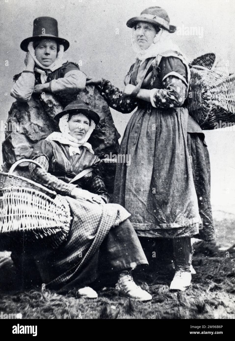 Three cockle women of South Wales, in a posed photograph.  They are probably from the coastal village of Llangwm, near Haverfordwest, Pembrokeshire, Dyfed, South Wales.  Llangwm cockle women habitually walked their wares to markets and fairs, often as far afield as Carmarthen. Stock Photo