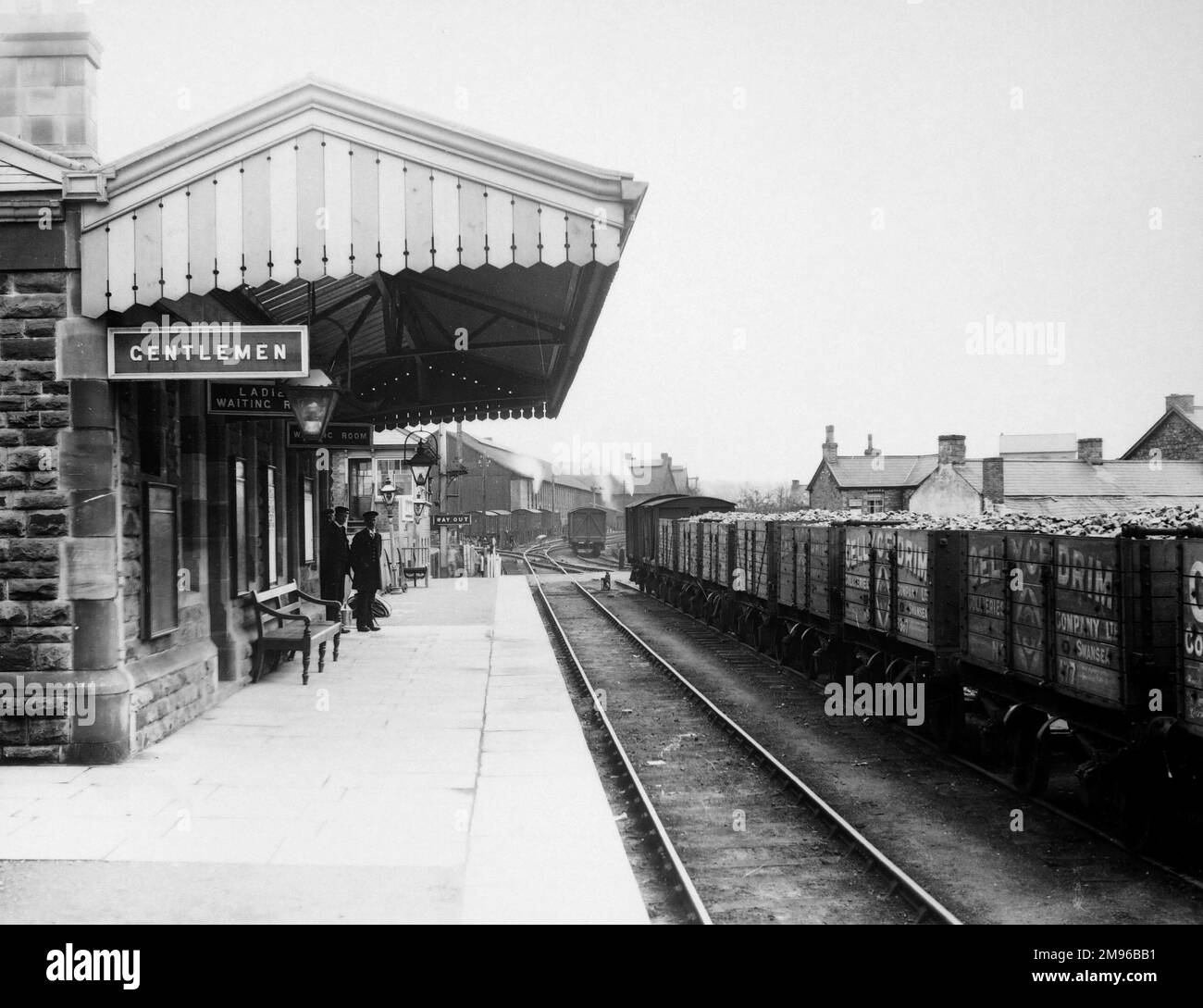View along the platform of Glanamman (or Glanaman) Railway Station in Carmarthenshire, South Wales, on the Great Western Railway.  Two of the station staff can be seen partway along the platform, and trucks loaded with coal are on the line on the right. Stock Photo