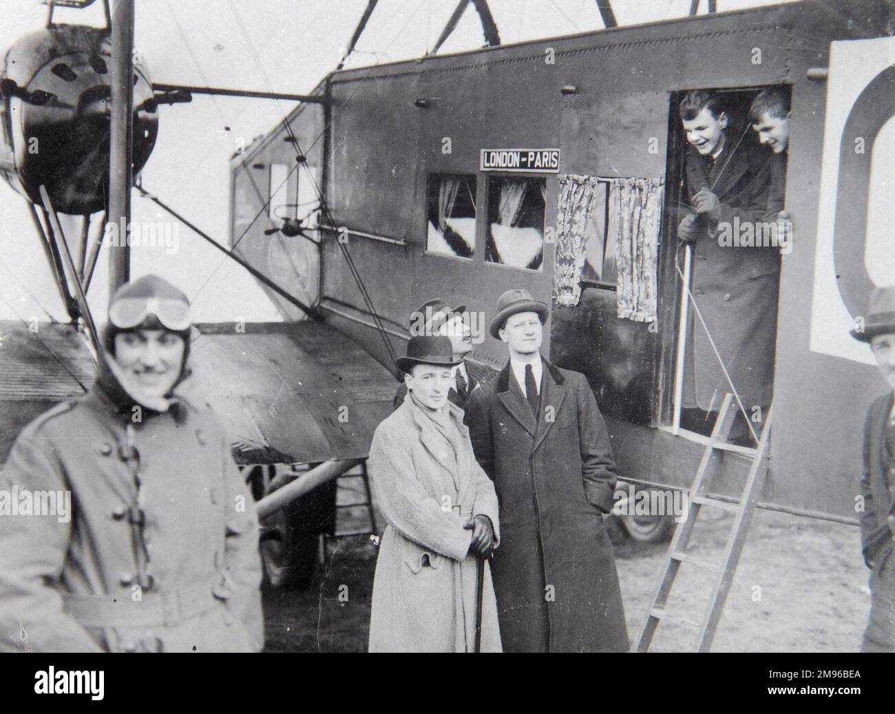 A group of passengers with an aircraft taking them on a London to Paris flight, in the early days of aviation.  The pilot stands on the left, with his goggles up on his forehead. The aircraft is a Handley Page O/400, converted as an airliner to shuttle dignitaries between London and Paris for the Treaty of Versailles negotiations. Stock Photo