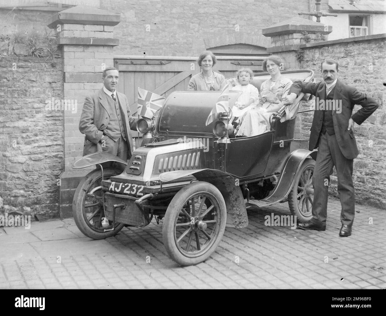 A proud family with their 1903-4 De Dion Bouton motor car, registration AJ 232, in a back yard in Crickhowell, Powys, Mid Wales. Stock Photo