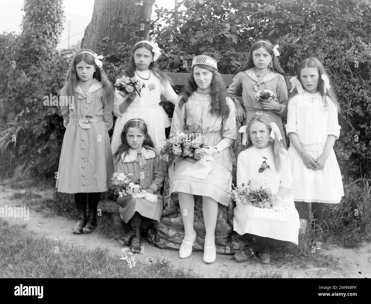 Seven sisters pose for their photograph in a garden, probably in the