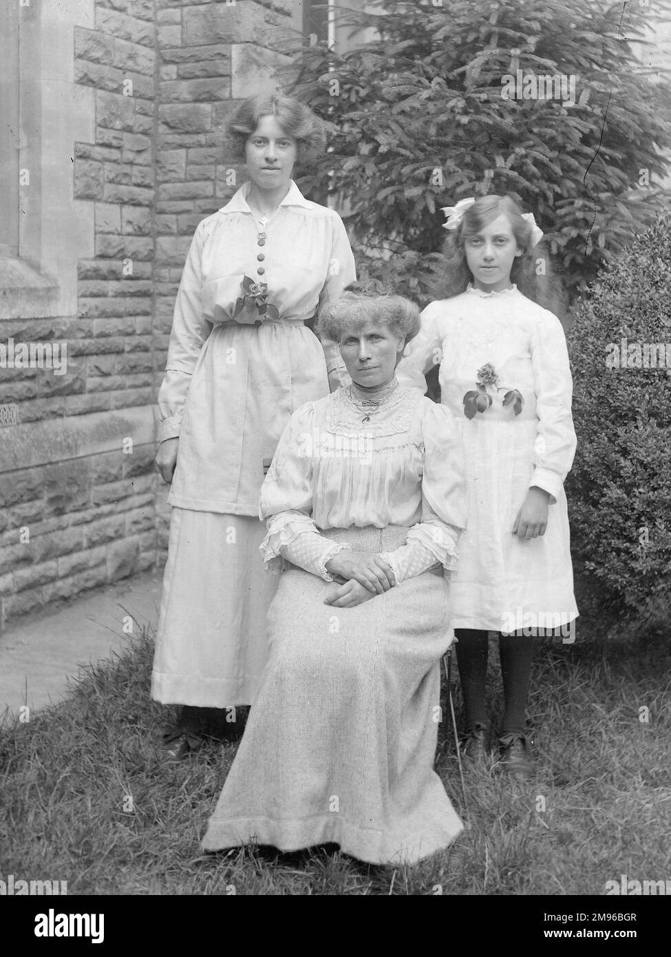 Three middle class Edwardian women, from three generations of one family, pose for a photograph in a garden, probably in the Mid Wales area. Stock Photo