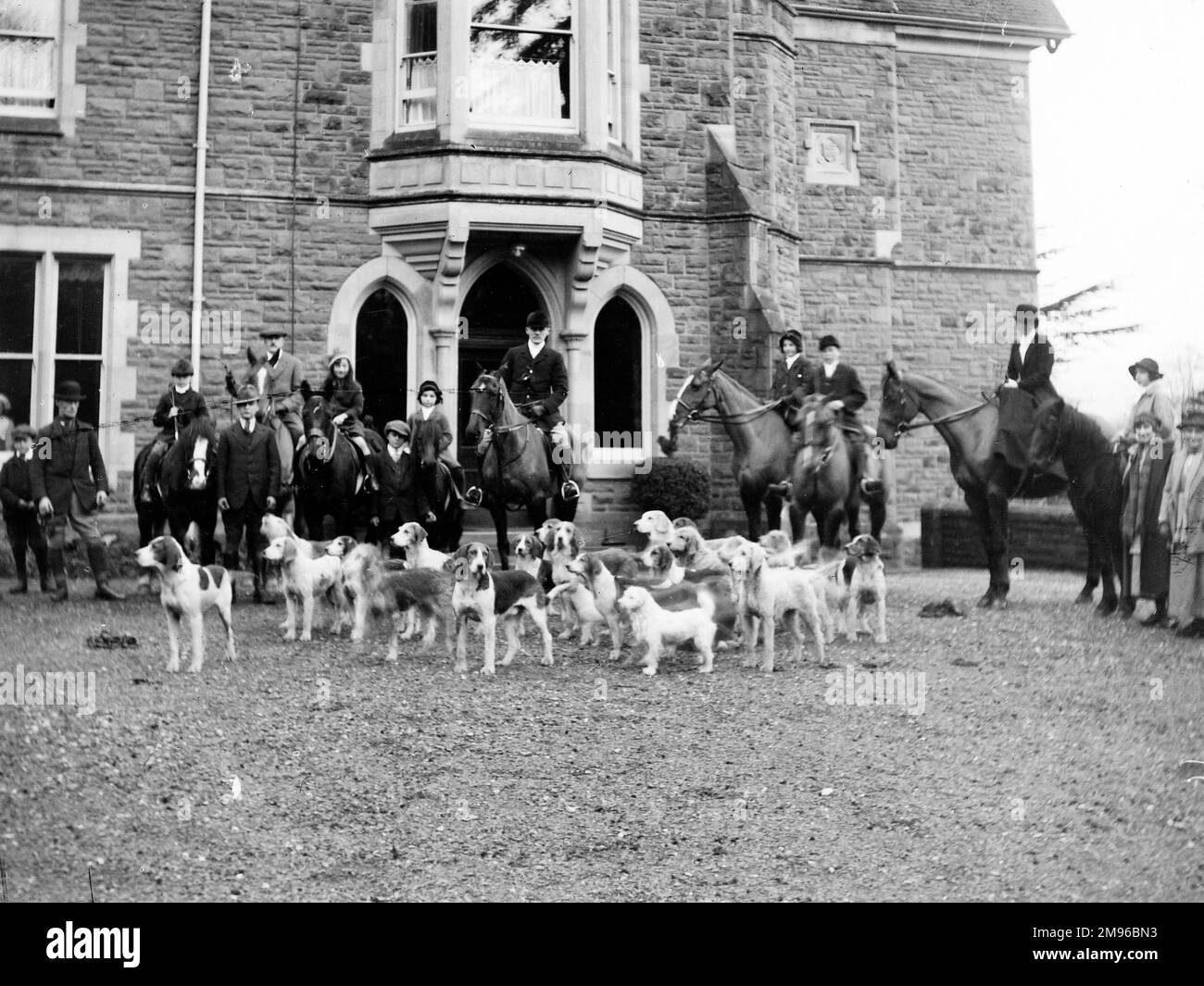 Members of the Crickhowell Harriers Hunt with horses and hounds in Powys, Mid Wales.  The building in the background is possibly the Old Rectory in the nearby village of Llangattock. Stock Photo