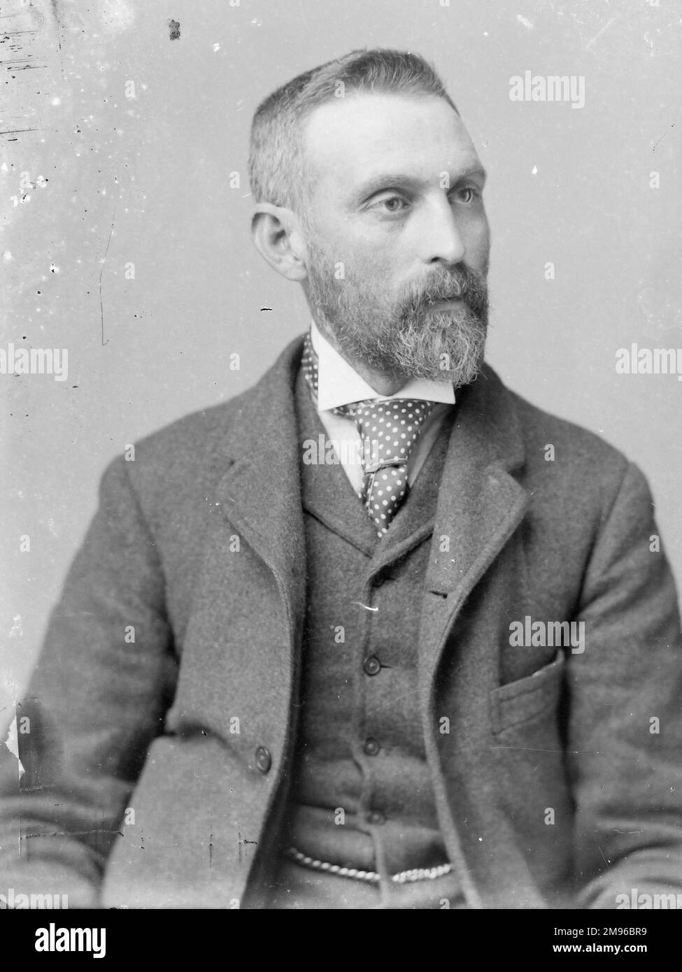 A middle aged man poses in the photographer's studio, Mid Wales.  He has a pointed beard, and wears a three-piece suit, with a spotty tie and wing collar. Stock Photo