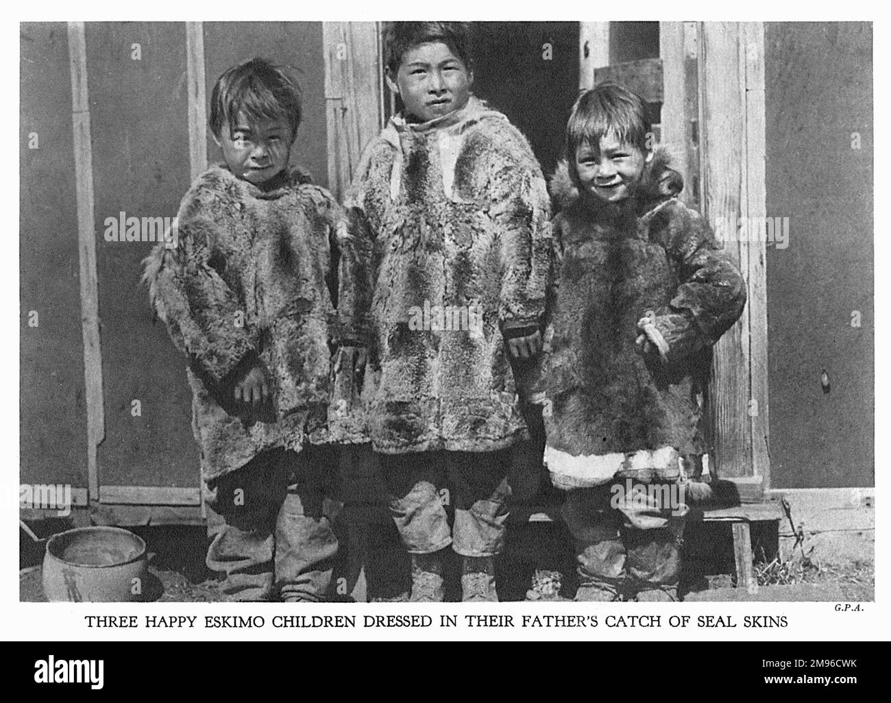 Three happy eskimo children dressed in their father's catch of seal ...