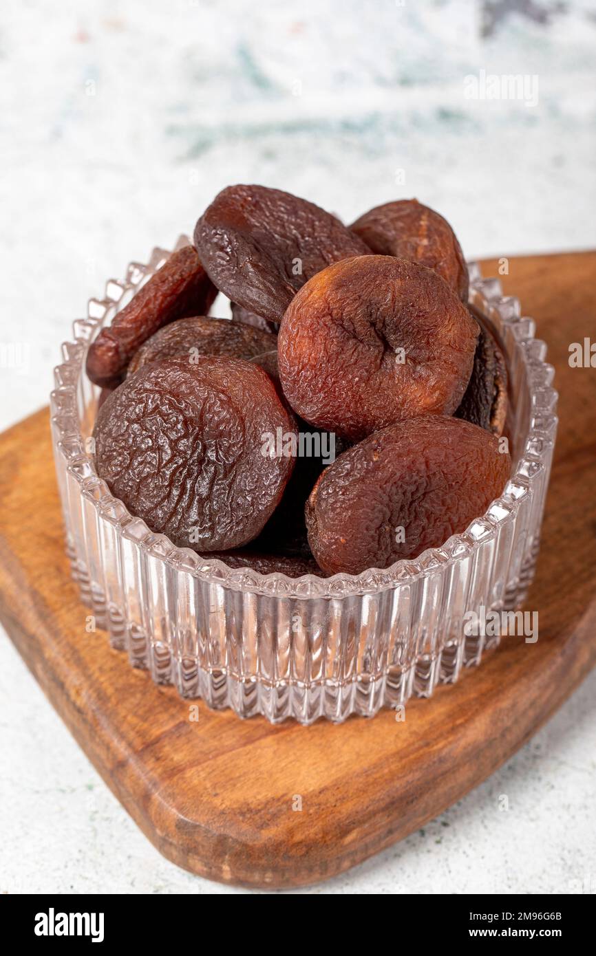 Dried apricots on stone background. Dark dried apricots in a glass bowl