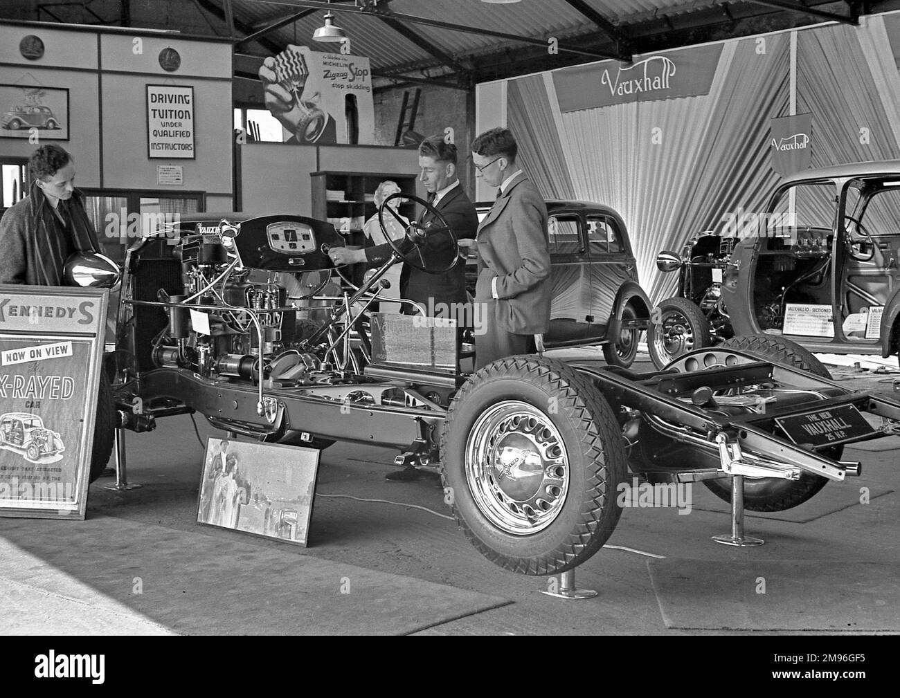 Scene in a car showroom, with a new Vauxhall 25 HP on display, stripped down to its engine. Stock Photo