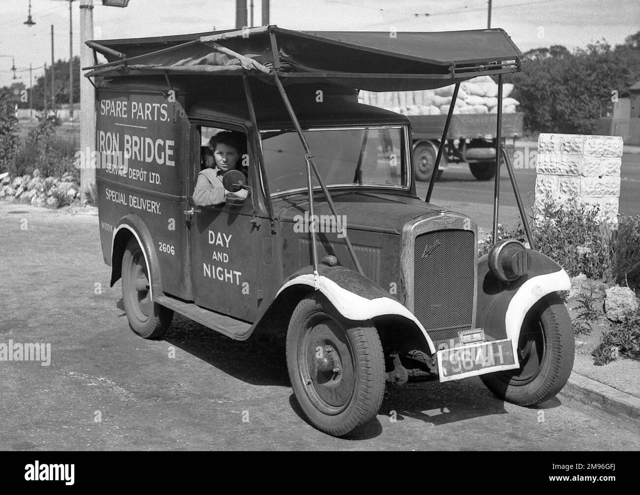 A woman driving a delivery van marked Spare Parts, Iron Bridge Service Depot Ltd, Special Delivery, Middx 2606, Day and Night. Stock Photo