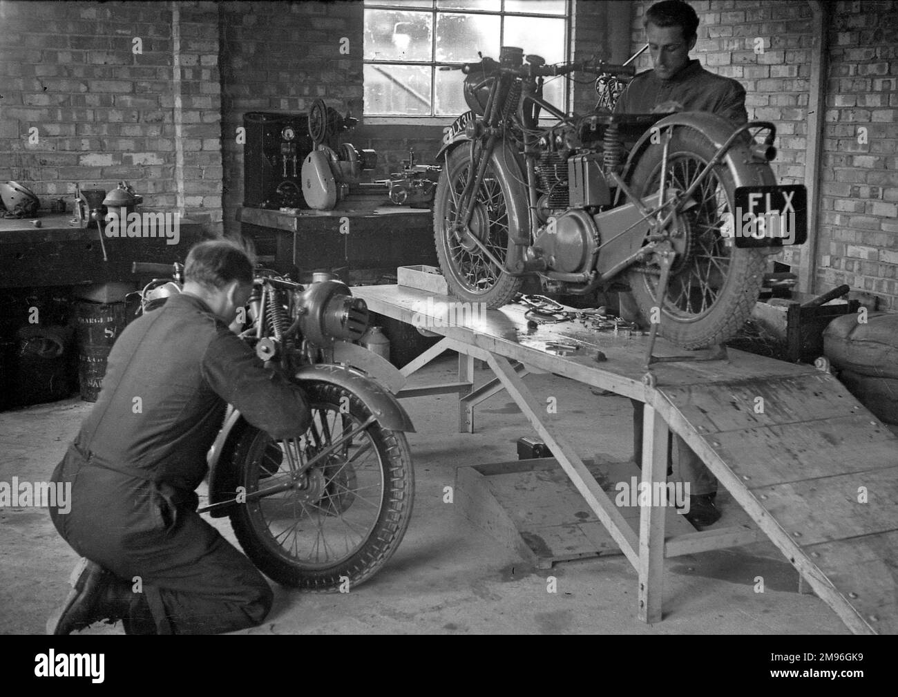 Two men in a garage, repairing motorcycles. Stock Photo