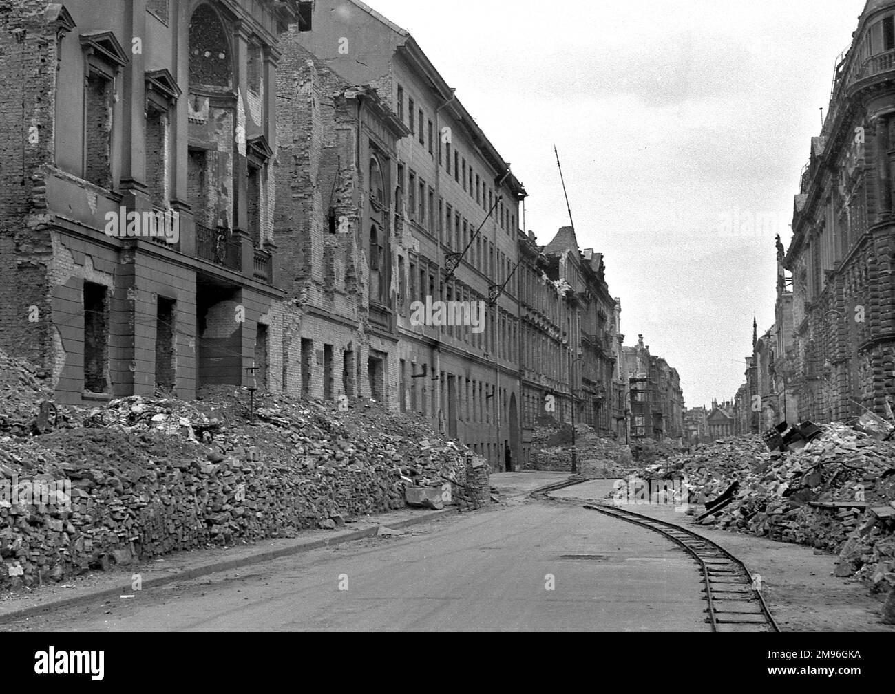 A bomb damaged street in Germany during the Second World War, with rubble piled up on either side of the road. Stock Photo
