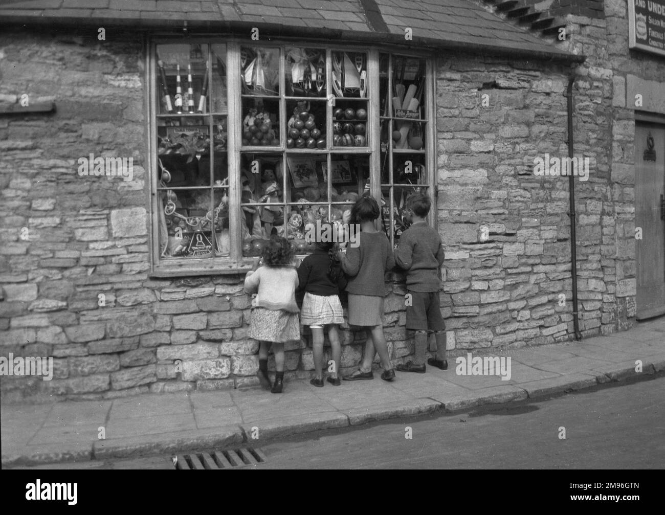 Four children gazing through a toy shop window. Stock Photo