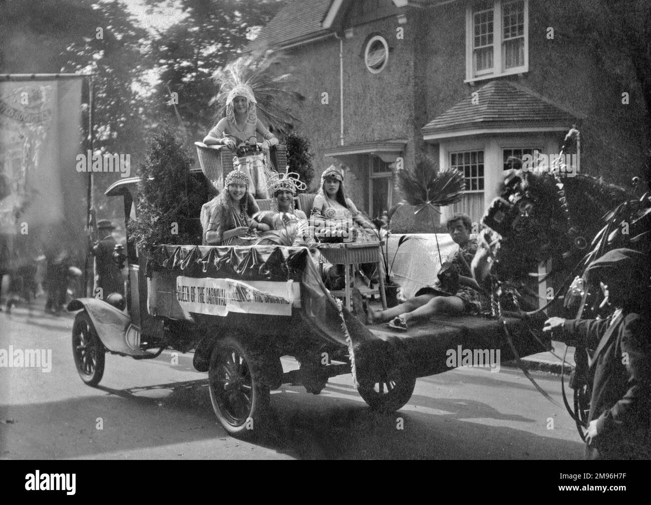 The Queen of the Carnival, dressed up to look like Cleopatra, riding along the road on the back of a truck, with four attendants. Stock Photo