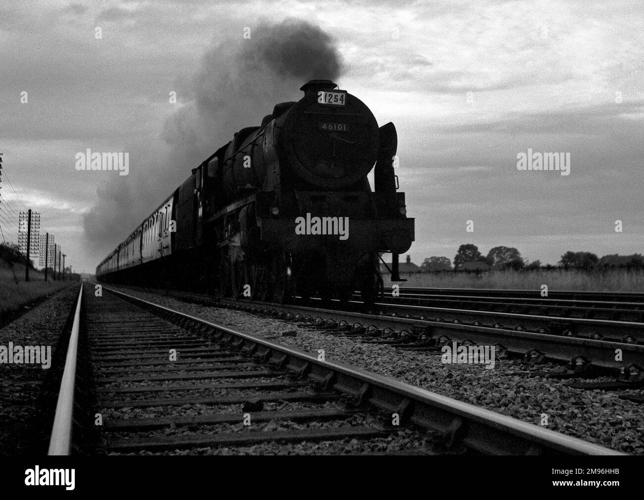 A steam train in motion, seen from ground level. Stock Photo