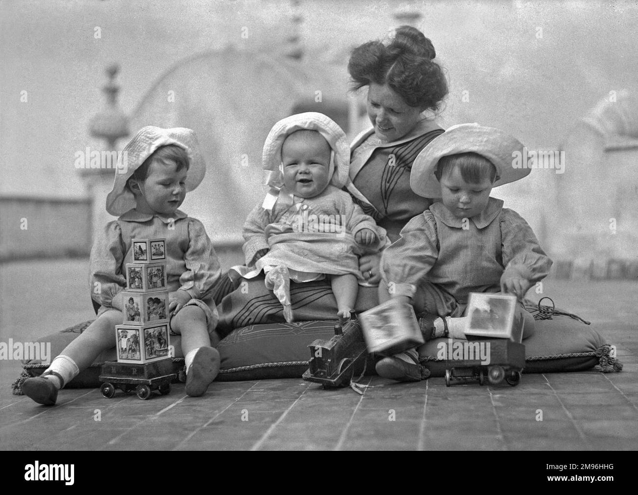 A mother and her three children sitting on cushions on the floor with