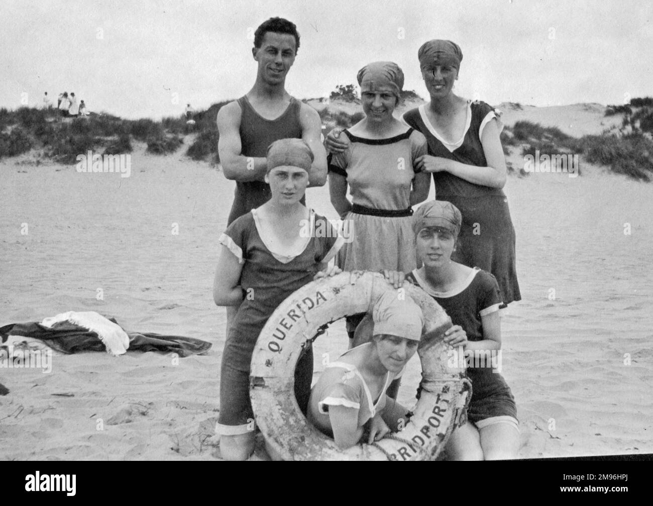 Six holidaymakers on a beach, probably at Querida, Bridport, Dorset. Stock Photo