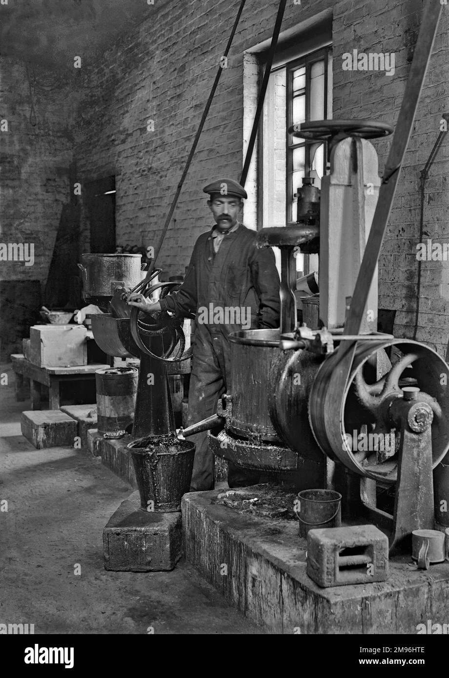 Workman in a factory operating machinery. The factory produced lead shrapnel for the use in high explosive artillery shells during WW1. Stock Photo