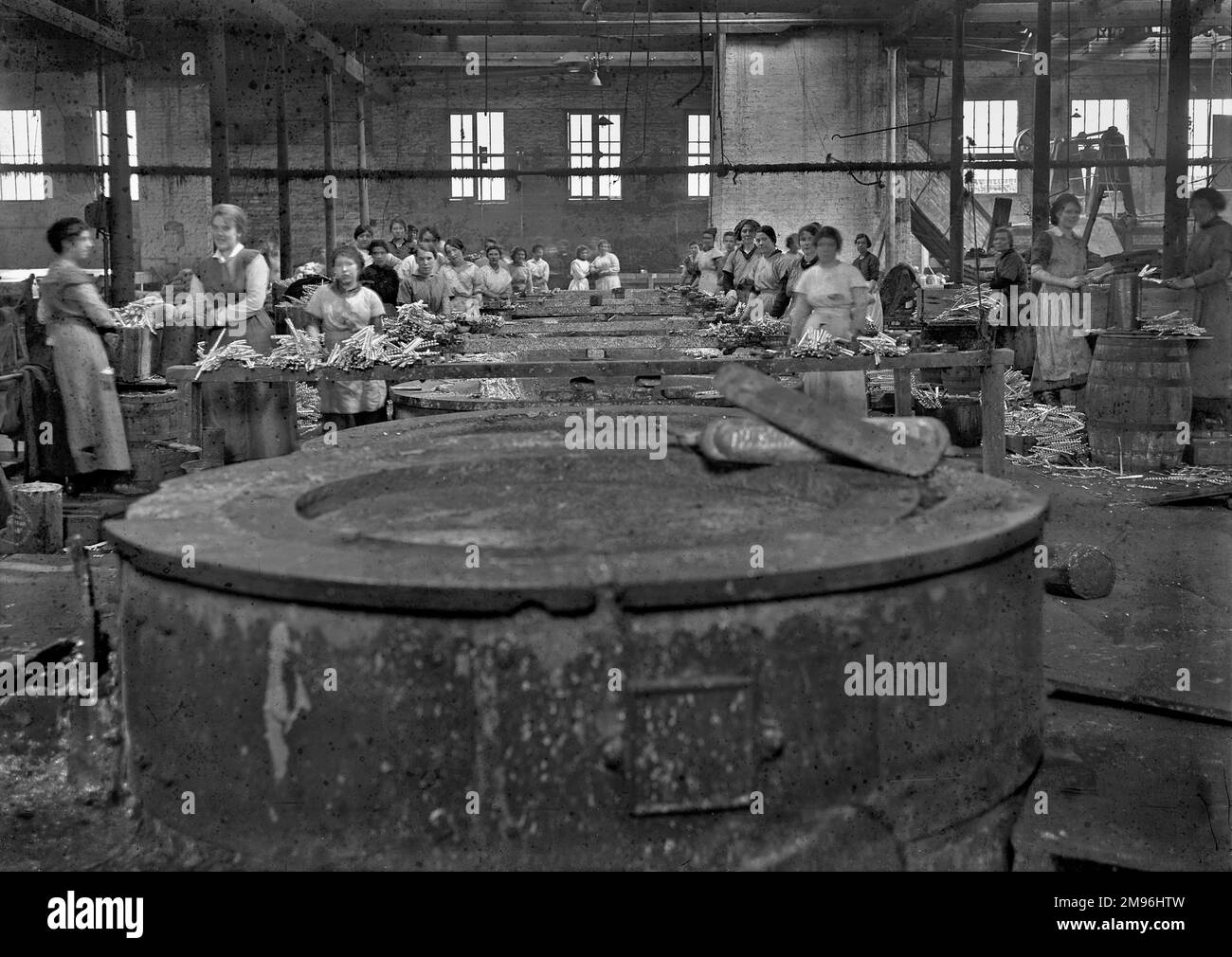 A group of female manual workers in a factory, standing close to vats containing molten lead, using in the manufacturing of shrapnel for WW1 artillery shells. Stock Photo