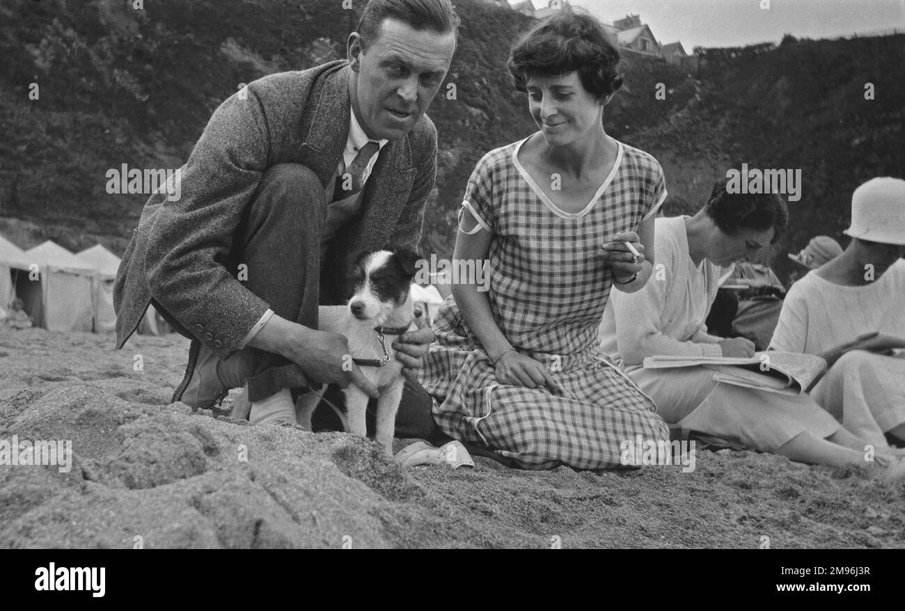 Couple with a terrier puppy on the beach at Newquay, Cornwall. Stock Photo