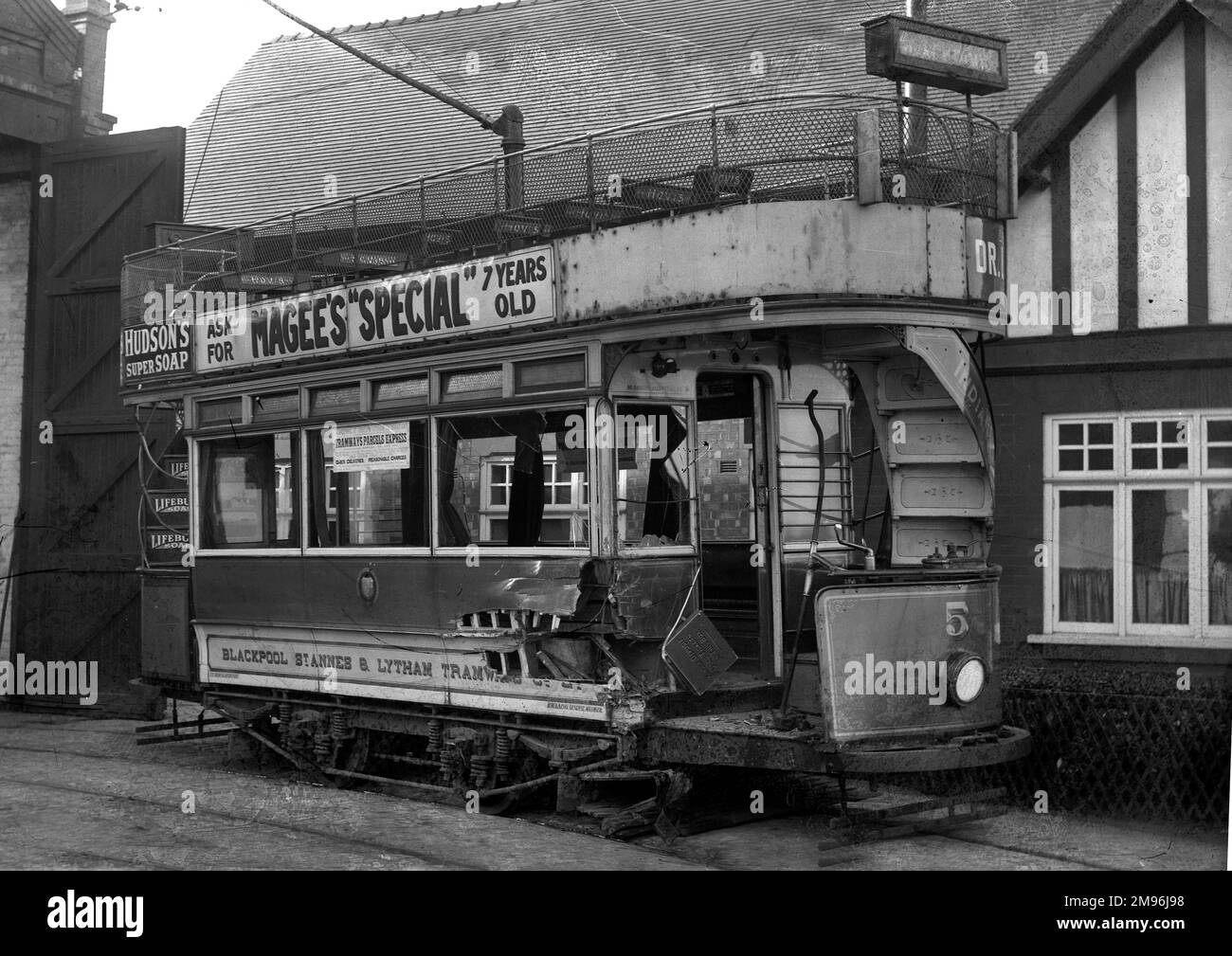 A disused tram of the Blackpool St Annes & Lytham Tramways, damaged and rusting in the open air.  It still carries advertising for Hovis, Lifebuoy Soap, Hudson's Super Soap, and Magee's Special (probably a brand of whisky). Stock Photo