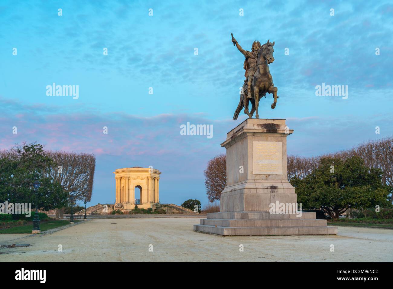 Colorful winter dawn landscape view of equestrian statue of king Louis XIV and ancient water tower in Promenade du Peyrou garden, Montpellier, France Stock Photo