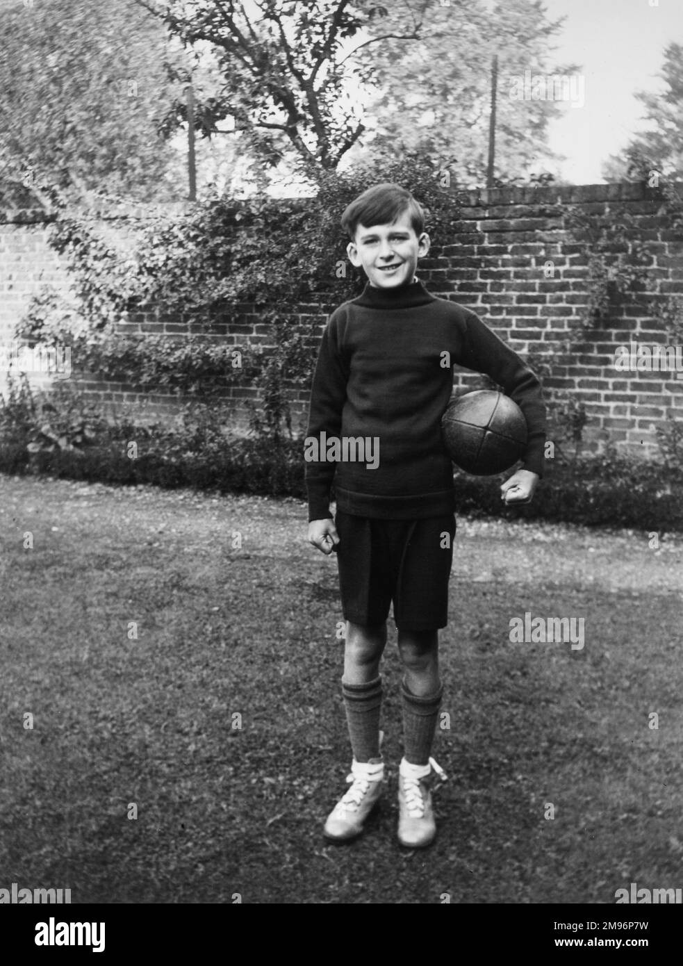 A boy standing in a garden wearing sports kit, with a rugby ball under his arm, at Eltham, south-east London. Stock Photo