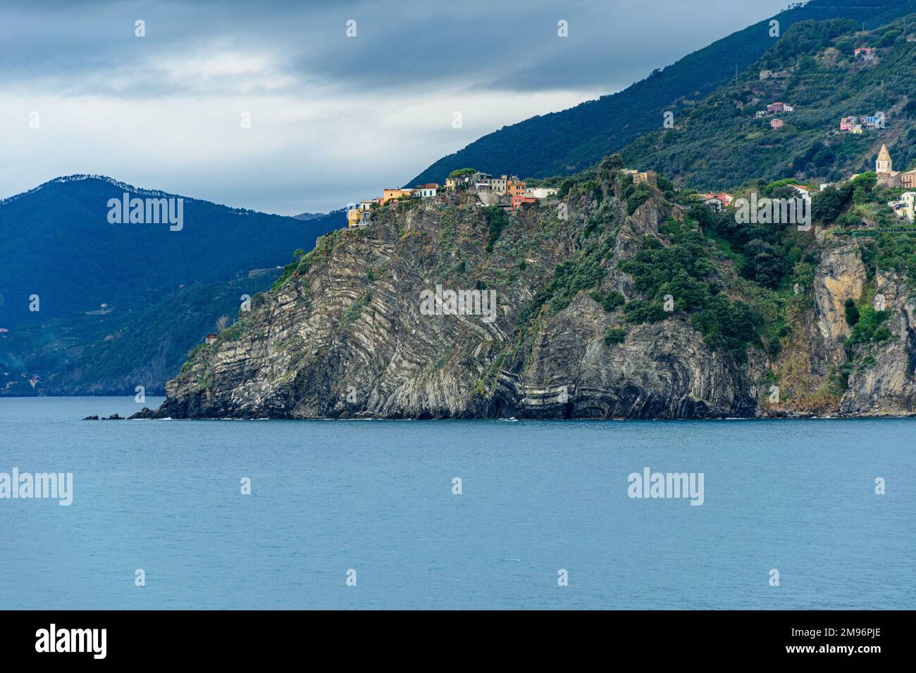 A view across to Corniglio, a cliff-top village on the Cinque Terra, Italy. Folds of strata are clearly seen in the cliffs beneath. Stock Photo